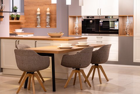 Gemütlicher Essbereich mit Holztisch und grauen Stühlen in einer modernen Küche mit weißen Schränken und Holzarbeitsplatte