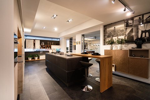 Ein modernes Küchenstudio mit einer dunklen Kücheninsel, hellen Holzarbeitsplatten und Barhockern