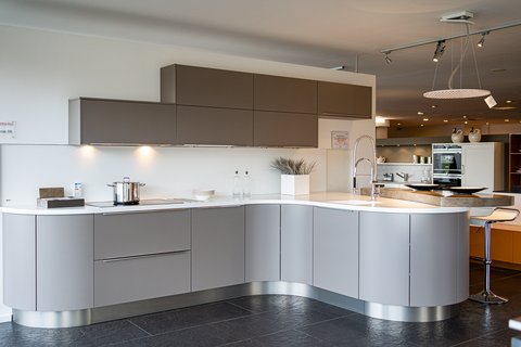 Moderne Küche mit hellgrauen, geschwungenen Unterschränken und dunklen Oberschränken