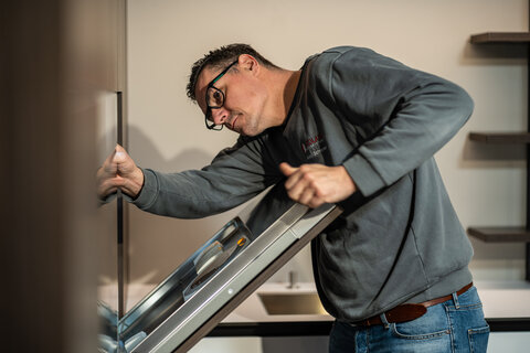 Ein Mitarbeiter montiert ein Element in einer modernen Küche in einem Küchenstudio